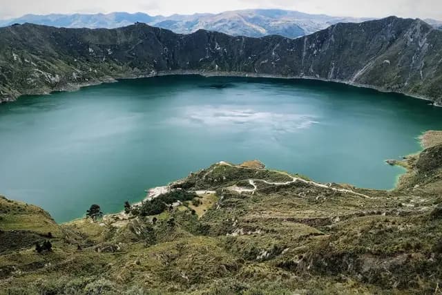 The turquoise Quilotoa crater lake ringed by the green walls of its volcanic caldera in the Ecuadorian Andes