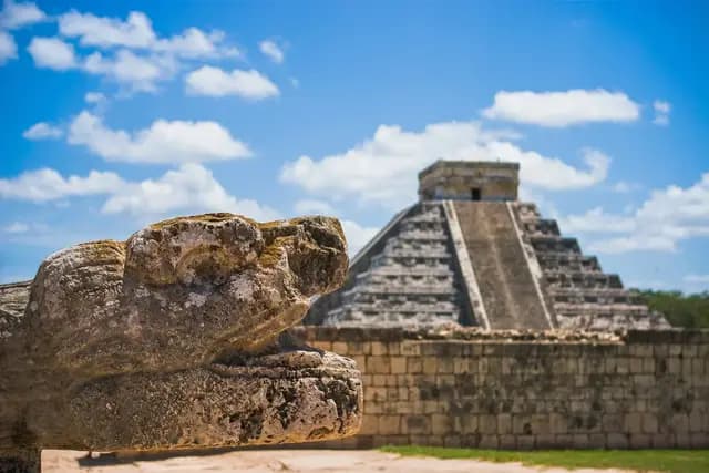 Chichén Itzá pyramid with carved stone serpent head in the foreground, Yucatán, Mexico