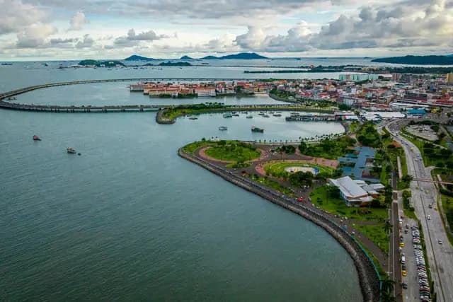 Aerial view of the Cinta Costera coastal loop curving past the red rooftops of Casco Viejo, Panama City