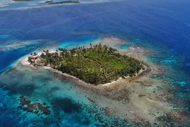 Aerial view of a palm-covered San Blas island surrounded by turquoise Caribbean waters, Panama