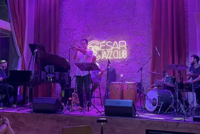 A jazz band performs on a stage under purple lights at Cesar Jazz Club.